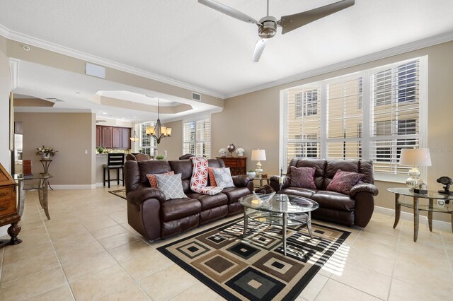 living room featuring ornamental molding, light tile flooring, ceiling fan with notable chandelier, and a raised ceiling