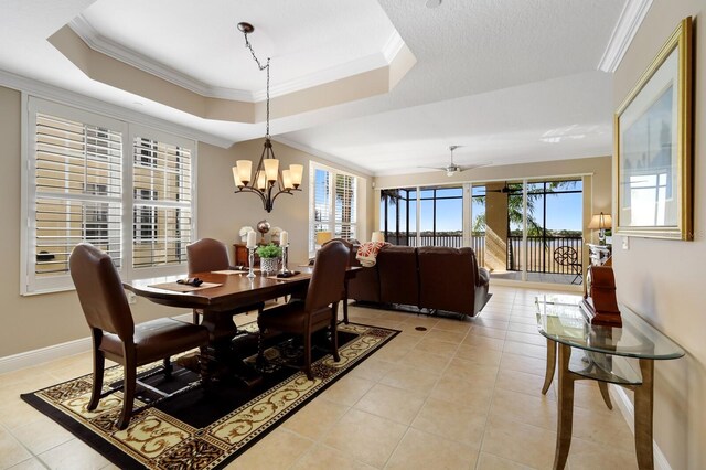 tiled dining area featuring ceiling fan with notable chandelier, ornamental molding, and a raised ceiling