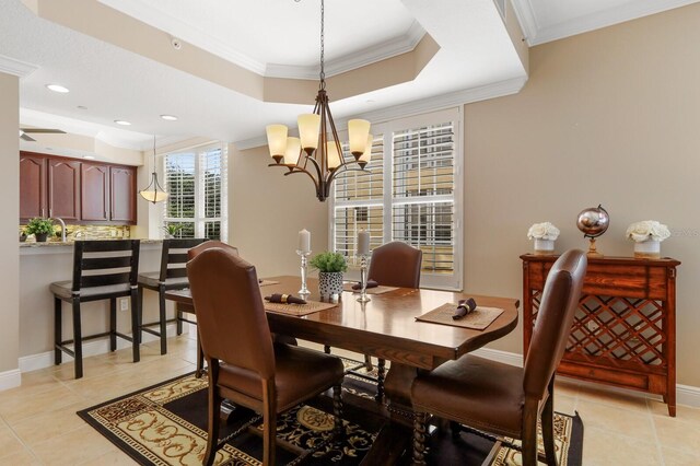 tiled dining area with ornamental molding, ceiling fan with notable chandelier, sink, and a tray ceiling