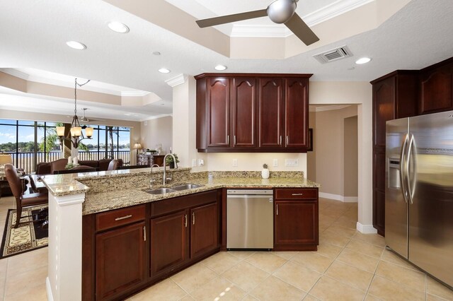 kitchen with appliances with stainless steel finishes, ceiling fan with notable chandelier, a raised ceiling, ornamental molding, and kitchen peninsula