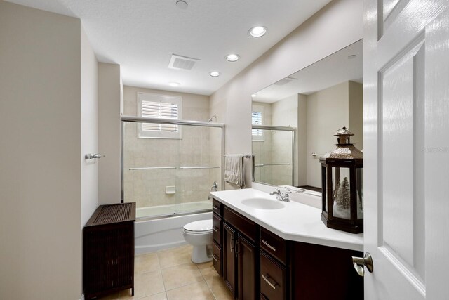 full bathroom featuring tile flooring, vanity, toilet, and shower / bath combination with glass door