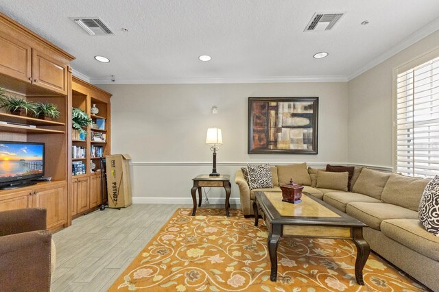 living room featuring crown molding, light wood-type flooring, and a textured ceiling