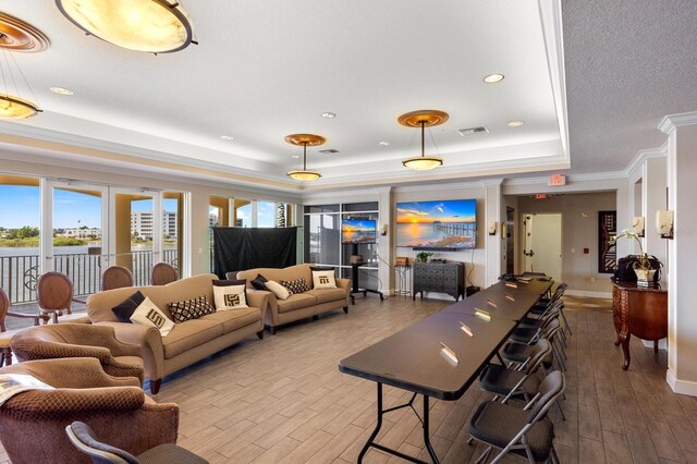 living room featuring hardwood / wood-style flooring, ornamental molding, and a raised ceiling