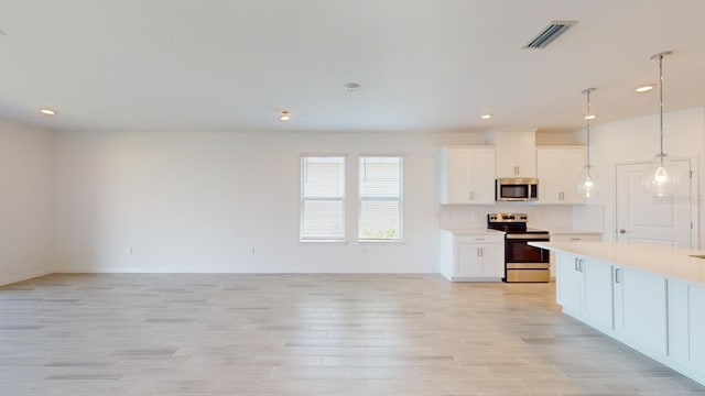 kitchen featuring white cabinets, decorative light fixtures, stainless steel appliances, and light hardwood / wood-style flooring