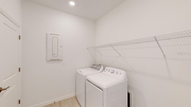 laundry area featuring independent washer and dryer, light wood-type flooring, and electric panel