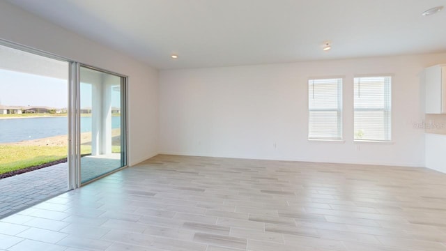 spare room with plenty of natural light, a water view, and light wood-type flooring