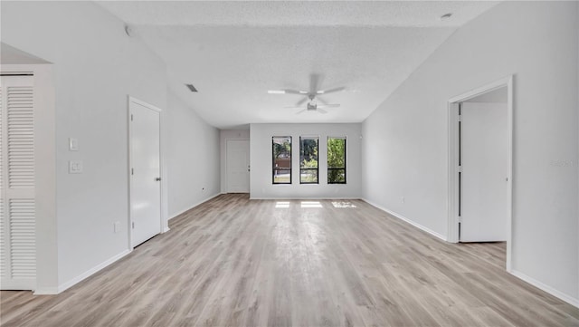 unfurnished room with a textured ceiling, ceiling fan, vaulted ceiling, and light wood-type flooring