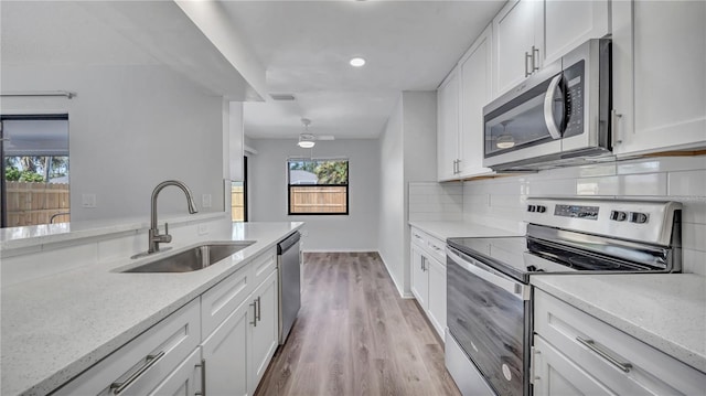 kitchen featuring appliances with stainless steel finishes, sink, light wood-type flooring, and white cabinetry