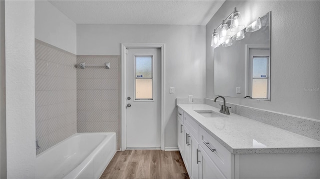 bathroom with tiled shower / bath, a textured ceiling, vanity, and hardwood / wood-style floors