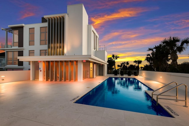 pool at dusk featuring a patio