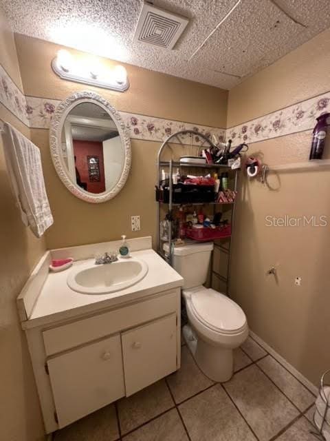 bathroom with toilet, oversized vanity, and tile flooring