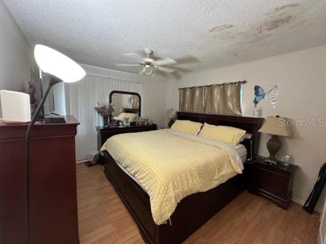 bedroom with a textured ceiling, hardwood / wood-style floors, and ceiling fan