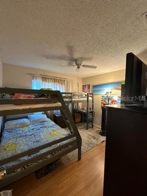 bedroom featuring hardwood / wood-style flooring, ceiling fan, and a textured ceiling