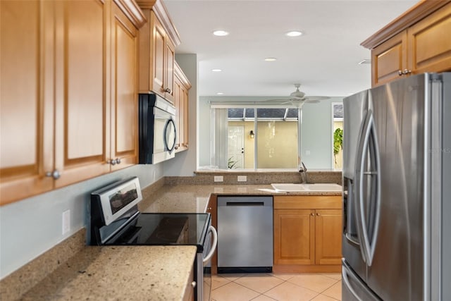 kitchen with light tile patterned flooring, sink, ceiling fan, light stone counters, and stainless steel appliances