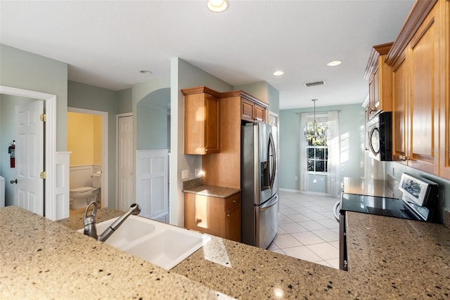 kitchen with pendant lighting, sink, light stone countertops, light tile patterned flooring, and stainless steel appliances