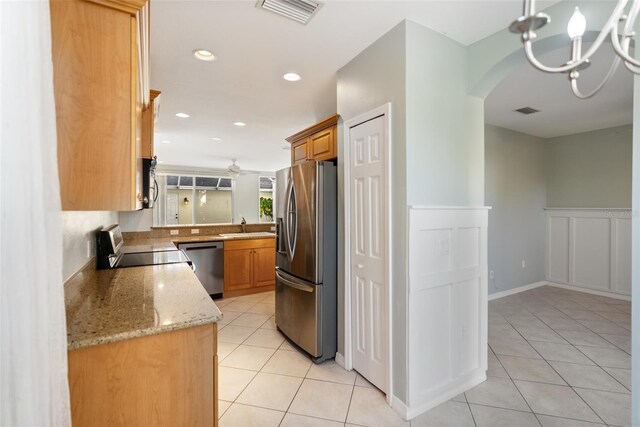 kitchen with light tile patterned flooring, sink, a chandelier, appliances with stainless steel finishes, and light stone countertops