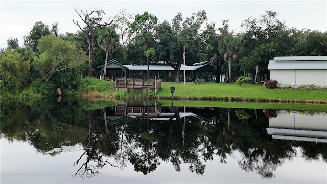 view of dock with a yard and a water view