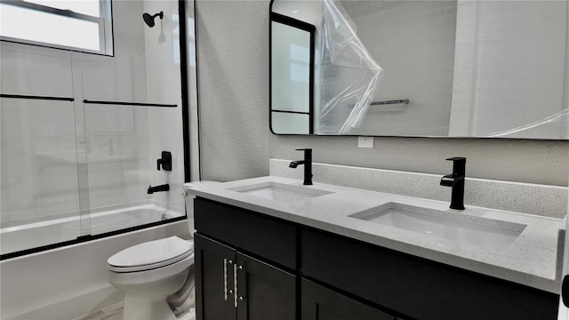 full bathroom with bath / shower combo with glass door, vanity, and toilet