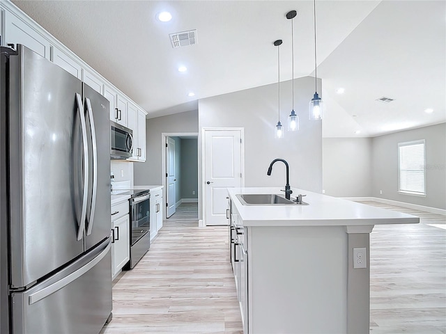 kitchen with an island with sink, sink, white cabinetry, appliances with stainless steel finishes, and vaulted ceiling