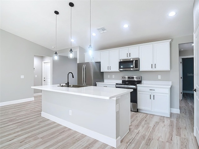 kitchen with an island with sink, lofted ceiling, appliances with stainless steel finishes, and decorative light fixtures