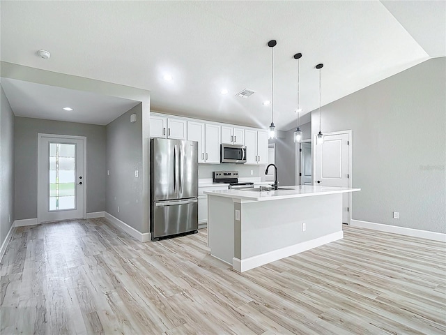 kitchen with white cabinetry, an island with sink, stainless steel appliances, lofted ceiling, and light hardwood / wood-style flooring