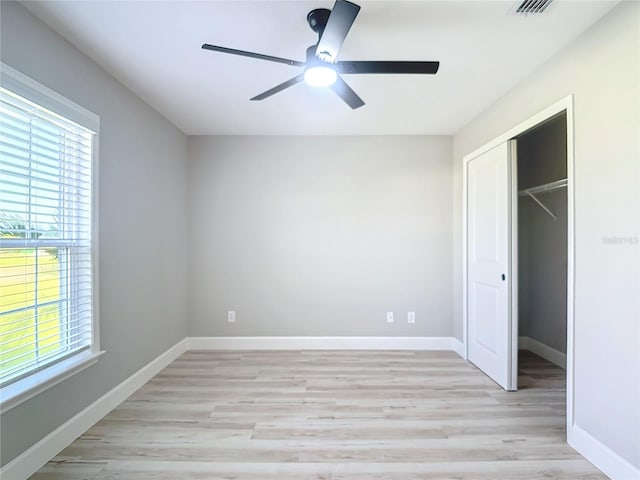 unfurnished bedroom featuring ceiling fan, light hardwood / wood-style flooring, a closet, and multiple windows