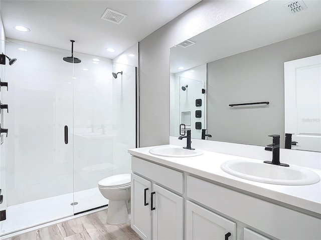 bathroom with hardwood / wood-style floors, vanity, a shower with shower door, and toilet