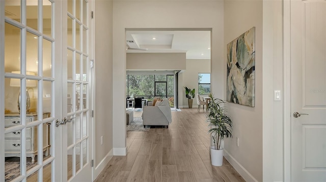 corridor with light hardwood / wood-style flooring, french doors, and coffered ceiling