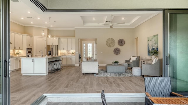 living room with a towering ceiling, sink, ornamental molding, ceiling fan, and coffered ceiling