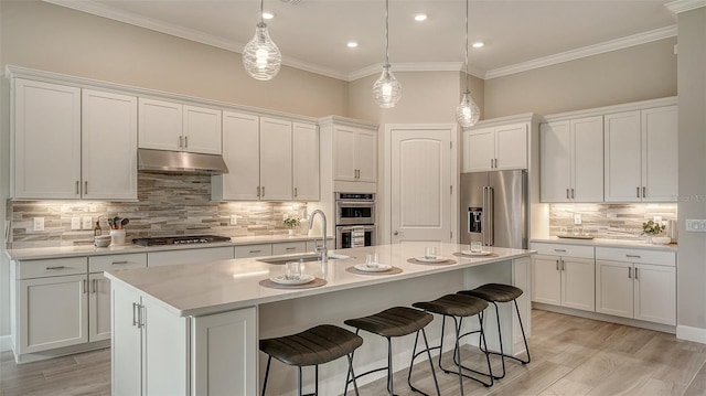 kitchen featuring white cabinetry, stainless steel appliances, an island with sink, sink, and backsplash