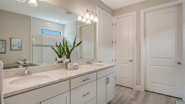 bathroom with vanity, a shower with shower door, and hardwood / wood-style floors