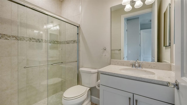 bathroom with a shower with shower door, toilet, and vanity