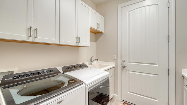 clothes washing area with sink, cabinets, light hardwood / wood-style flooring, and washer and dryer