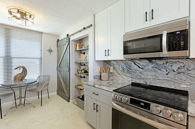 kitchen featuring white cabinets, a barn door, and appliances with stainless steel finishes