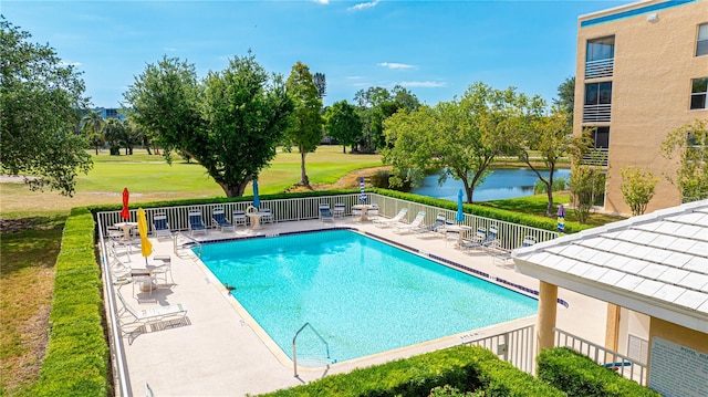 view of pool featuring a lawn, a water view, and a patio