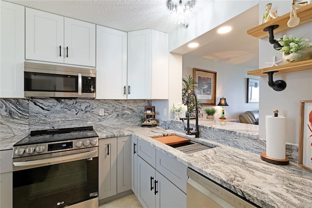 kitchen featuring backsplash, light stone counters, white cabinets, and appliances with stainless steel finishes