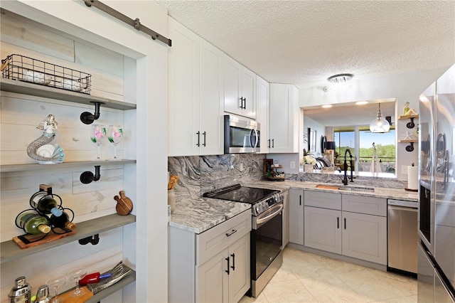 kitchen with sink, backsplash, pendant lighting, white cabinets, and appliances with stainless steel finishes