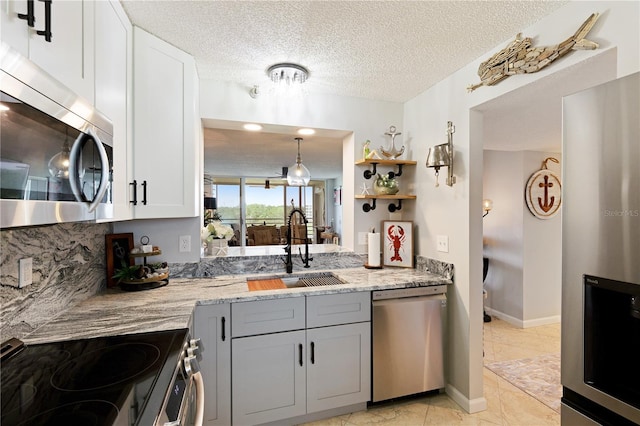 kitchen with light stone countertops, sink, stainless steel appliances, a textured ceiling, and white cabinets