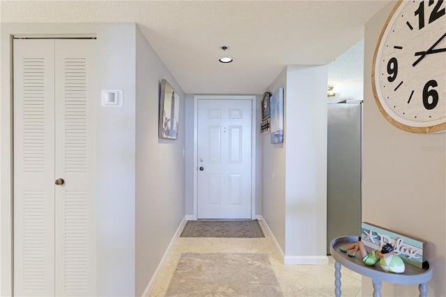 hall with light tile patterned floors and a textured ceiling