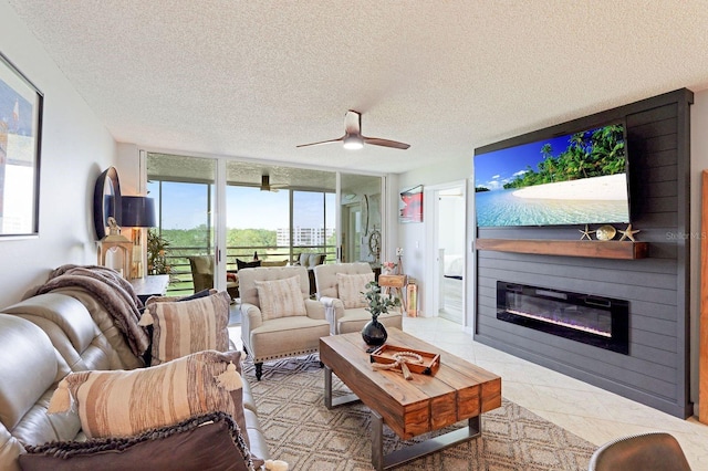 living room with floor to ceiling windows, ceiling fan, a large fireplace, and a textured ceiling