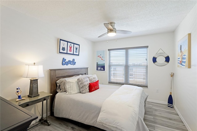 bedroom with ceiling fan, a textured ceiling, and light wood-type flooring