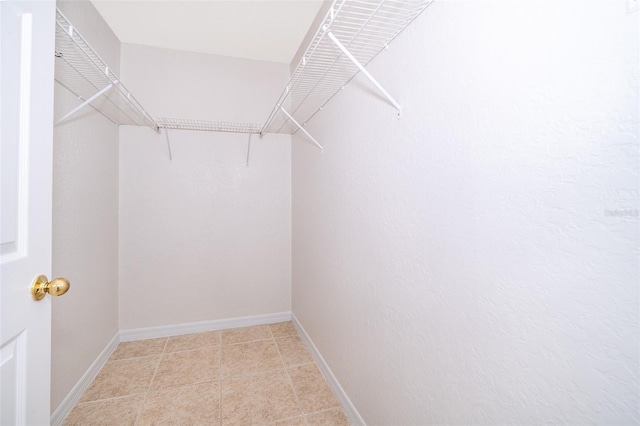 walk in closet with light tile floors