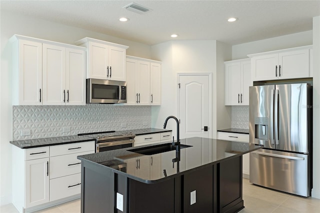 kitchen featuring backsplash, a center island with sink, white cabinets, sink, and stainless steel appliances