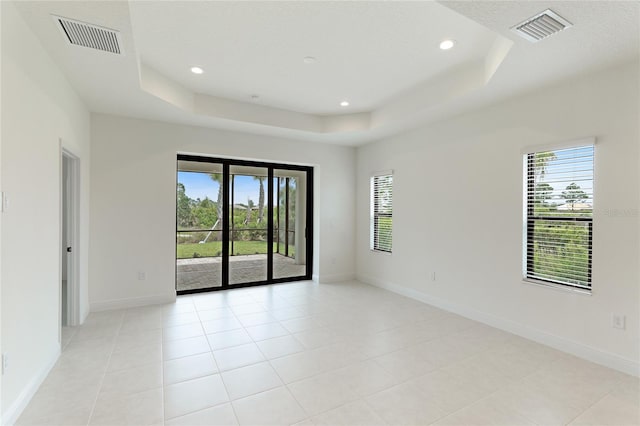 empty room with light tile patterned floors and a tray ceiling