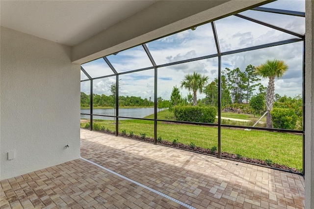 view of patio featuring glass enclosure and a water view