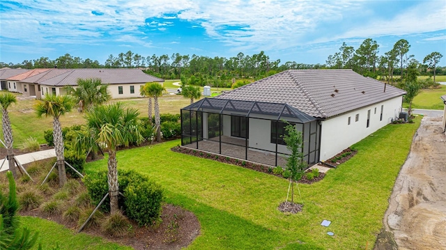 back of property with a lawn, glass enclosure, and central air condition unit