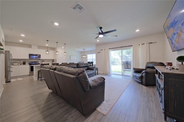 living room with light hardwood / wood-style flooring and ceiling fan