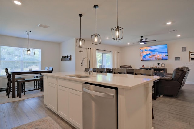 kitchen with ceiling fan, a kitchen island with sink, white cabinets, stainless steel dishwasher, and pendant lighting