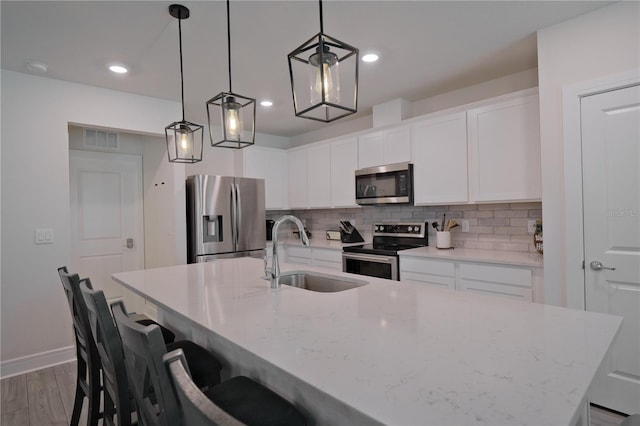 kitchen with stainless steel appliances, wood-type flooring, tasteful backsplash, sink, and pendant lighting