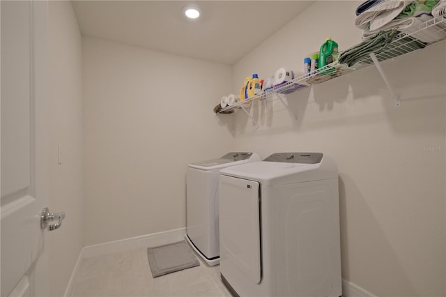 clothes washing area featuring light tile floors and washing machine and clothes dryer